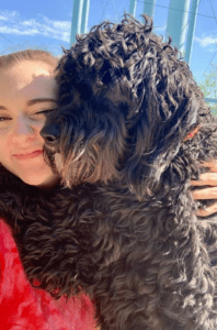 Woman smiling with curly shaggy black dog